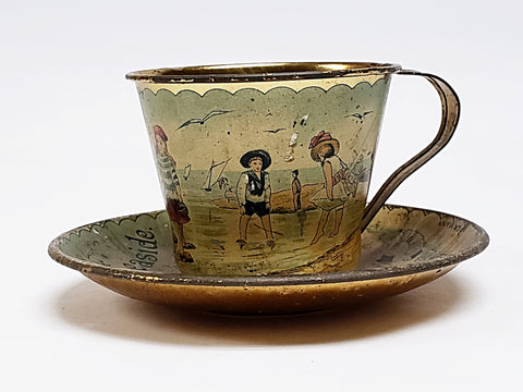 Early Tin Lithograph Cup and Saucer Gold Color Interior Soldered Handle - Ä Present from the Seaside"