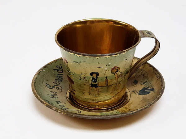 Early Tin Lithograph Cup and Saucer Gold Color Interior  - Ä Present from the Seaside"